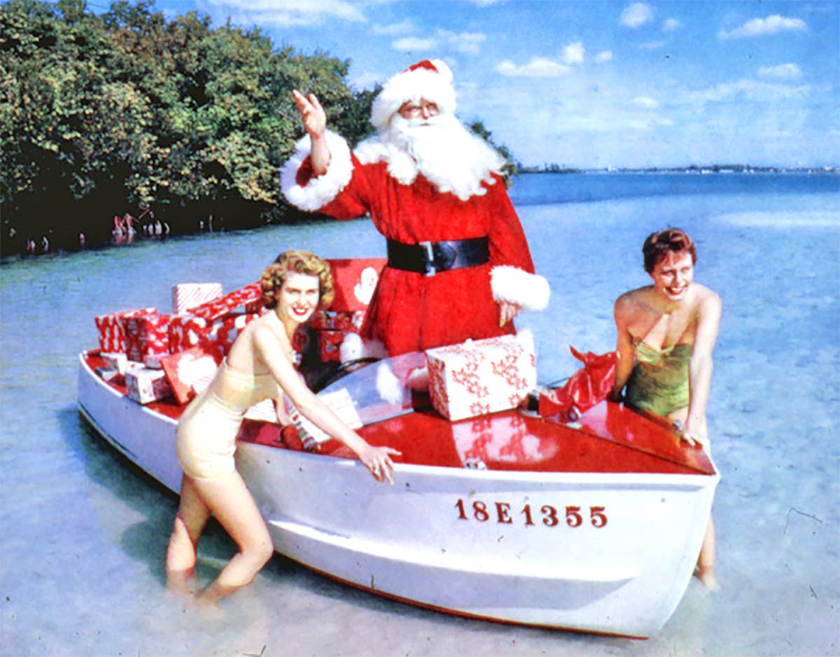 Santa Claus being brought ashore in a boat carrying gifts